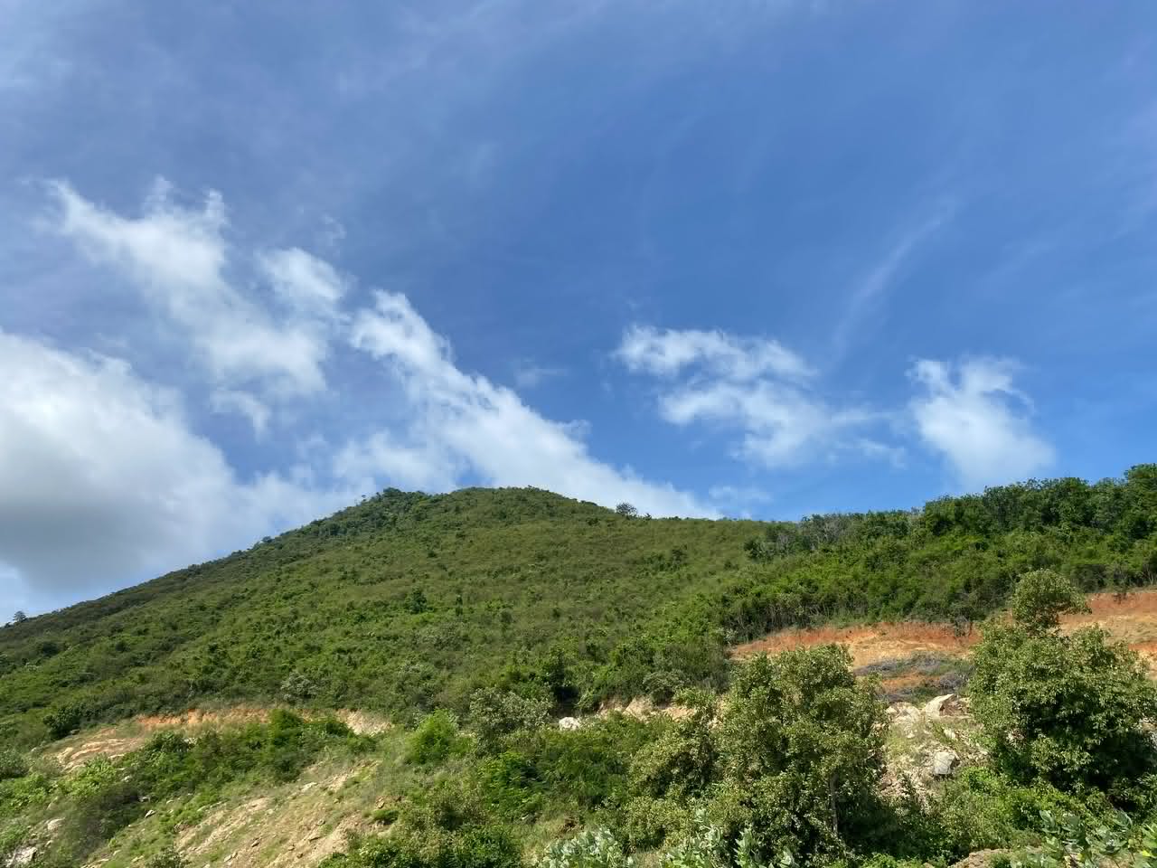 Green highland slopes beneath a bright, cloud-filled sky